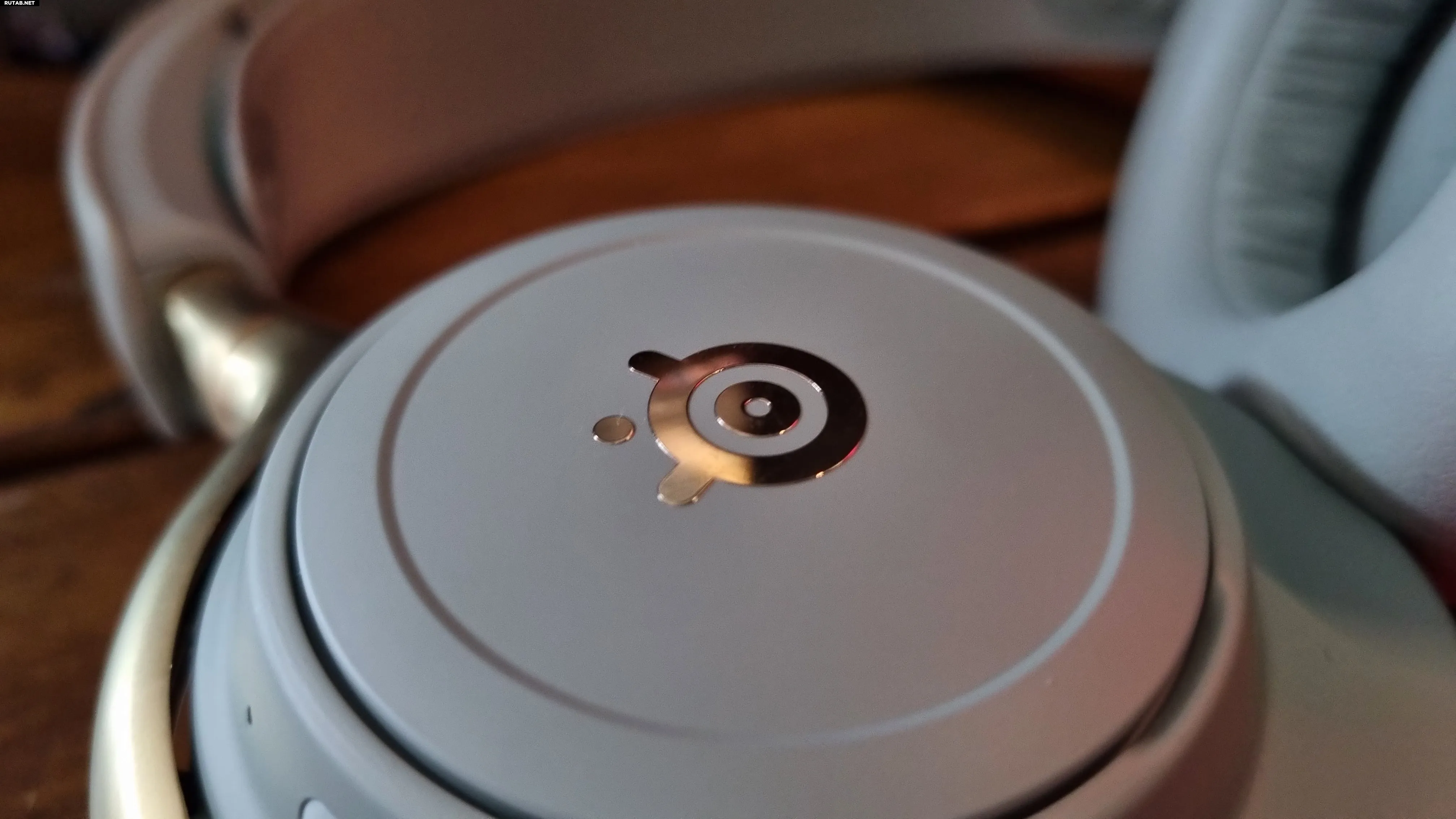 Золотой логотип SteelSeries на наушнике гарнитуры SteelSeries Arctis Nova Elite